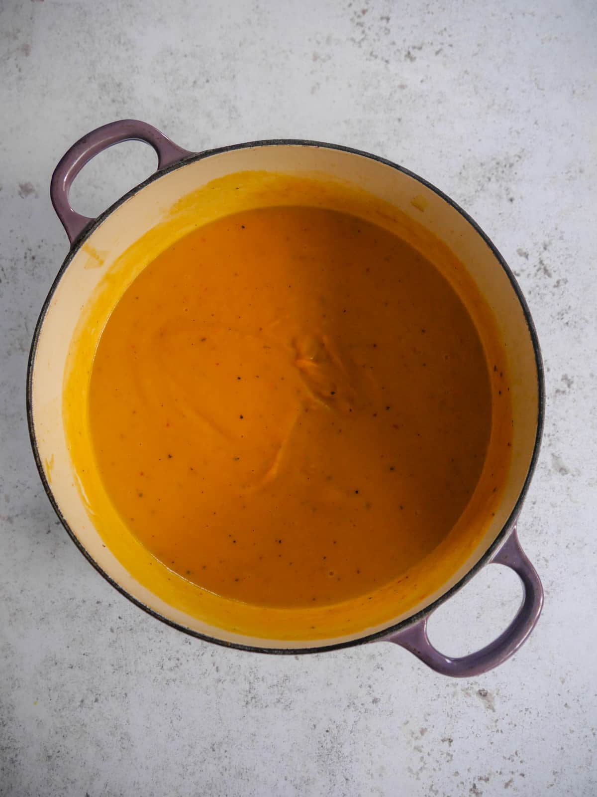 A Dutch oven filled with cooked sweet potato, coconut and chilli soup.