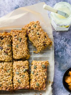 Almond apricot flapjacks cut up and set out on a sheet of baking parchment.