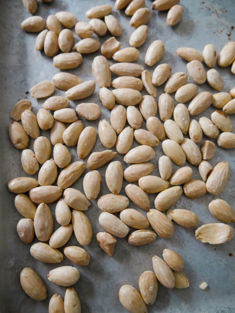 A baking sheet topped with raw blanched almonds.