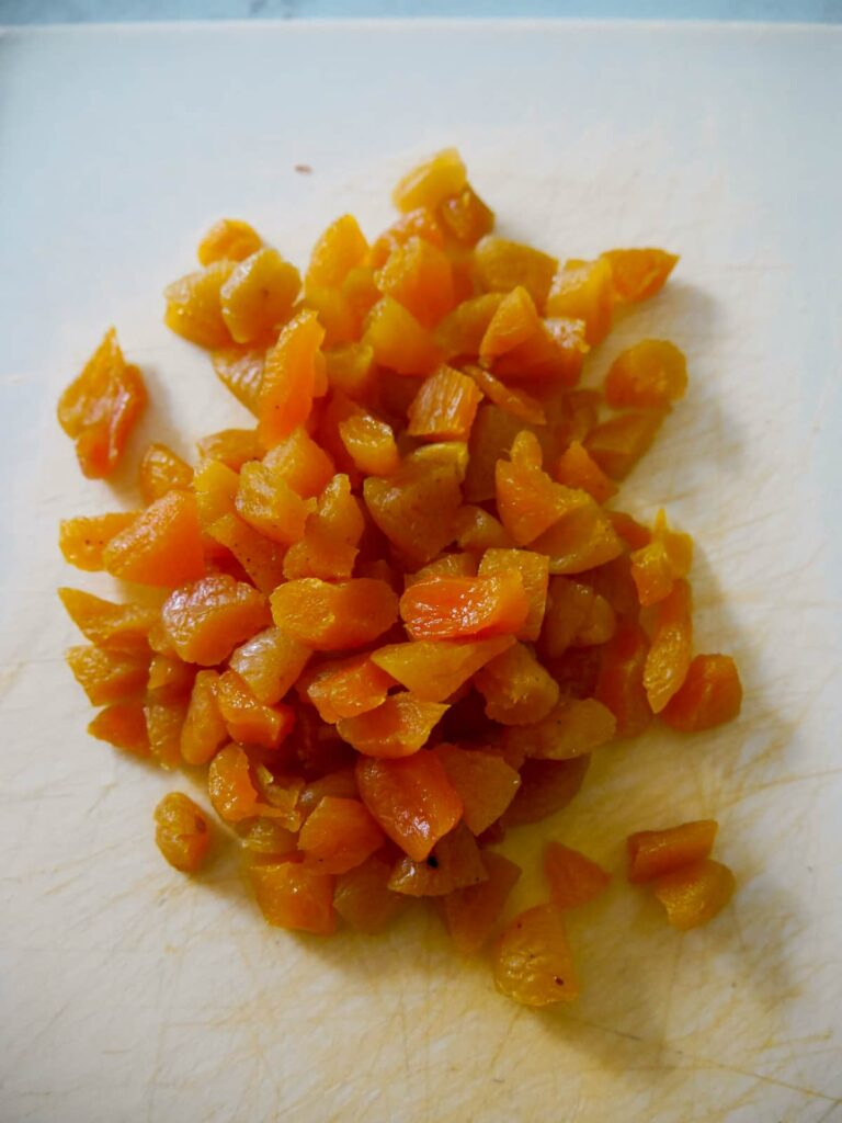 Pieces of chopped dried apricots on a chopping board.