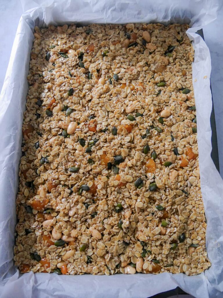 Flapjack mixture spread over a baking tray lined with parchment paper.