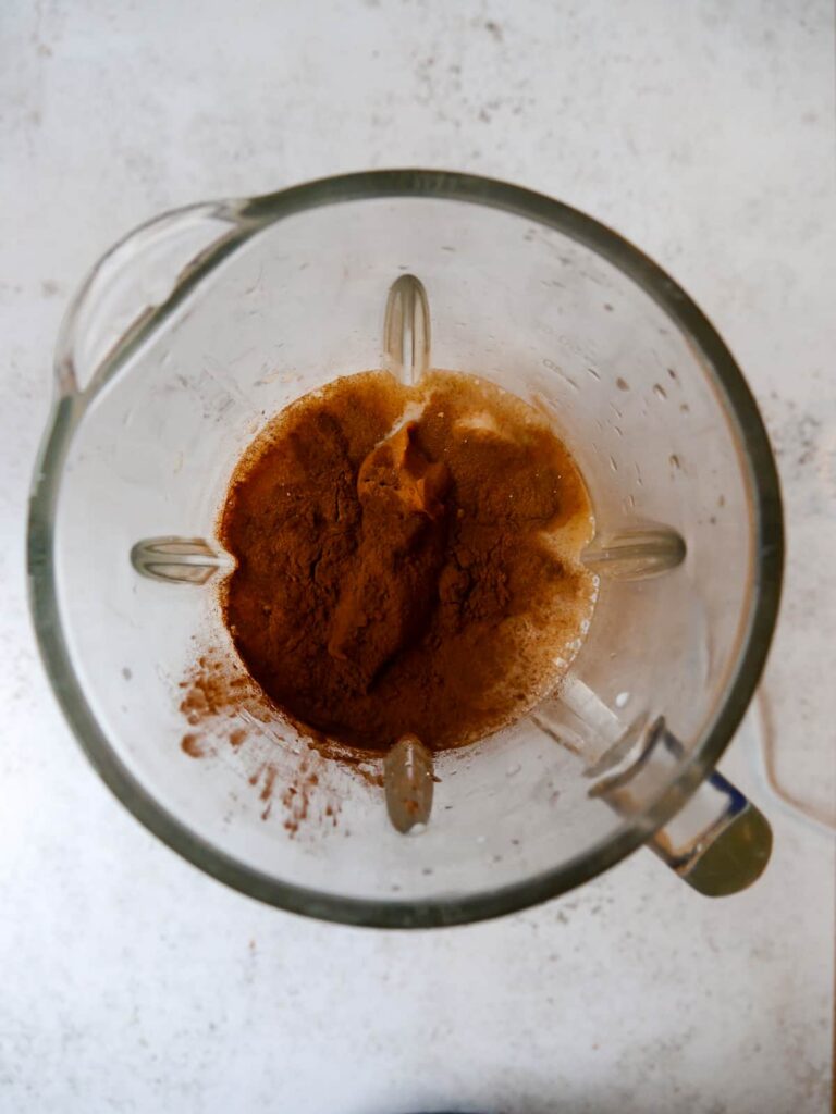 A blender jug filled with chocolate peanut butter smoothie ingredients.