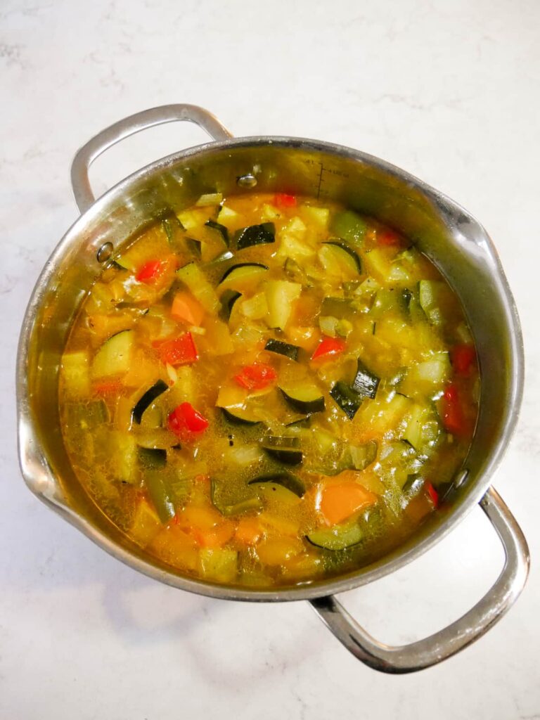 Large pan filled with cooked soup vegetables.