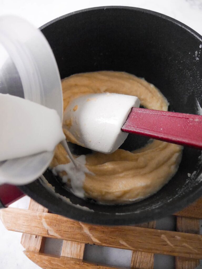 Milk being added to a saucepan of butter and flour roux.