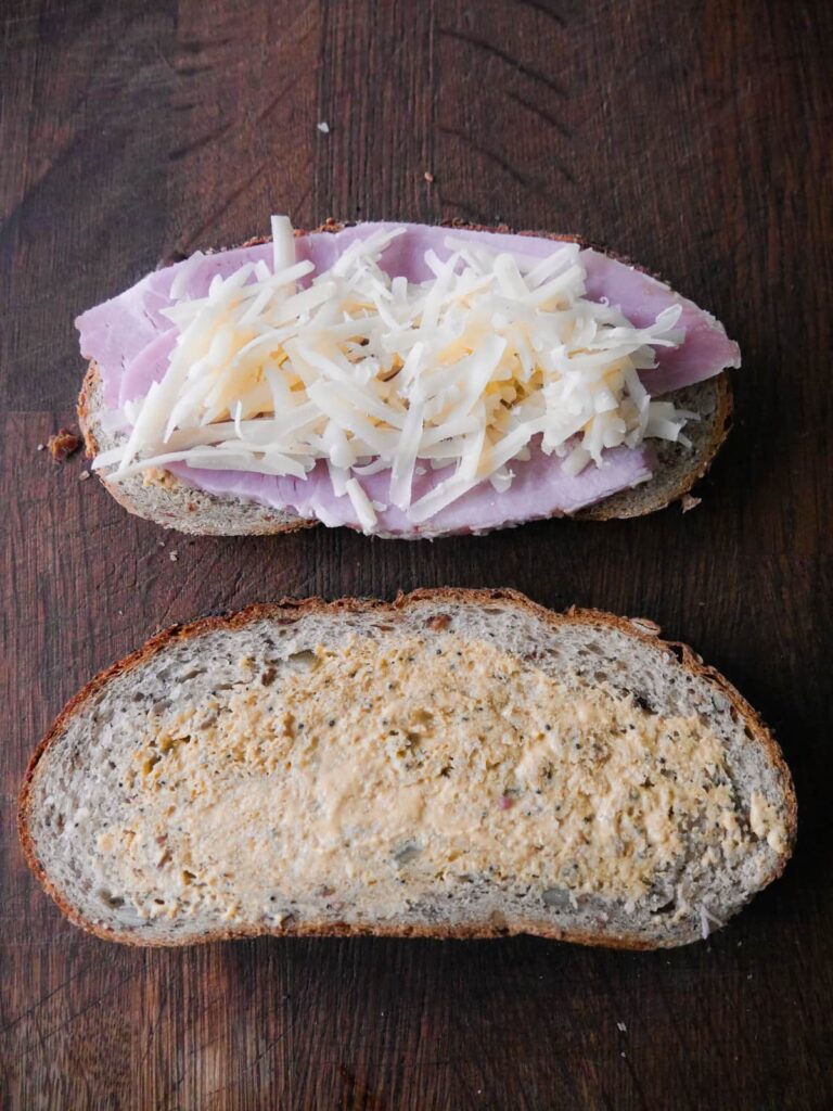 Sliced of seeded bread, spread with mustard and topped with sliced ham and grated cheese.