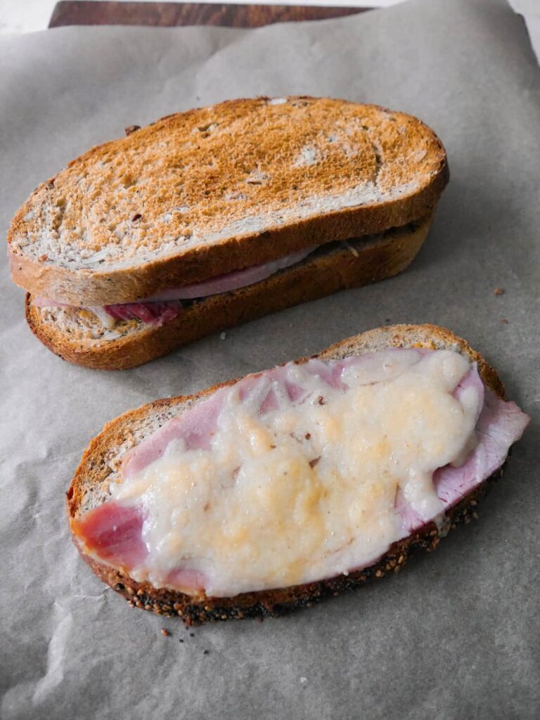 Toasted cheese and ham sandwiches on a sheet of baking parchment.