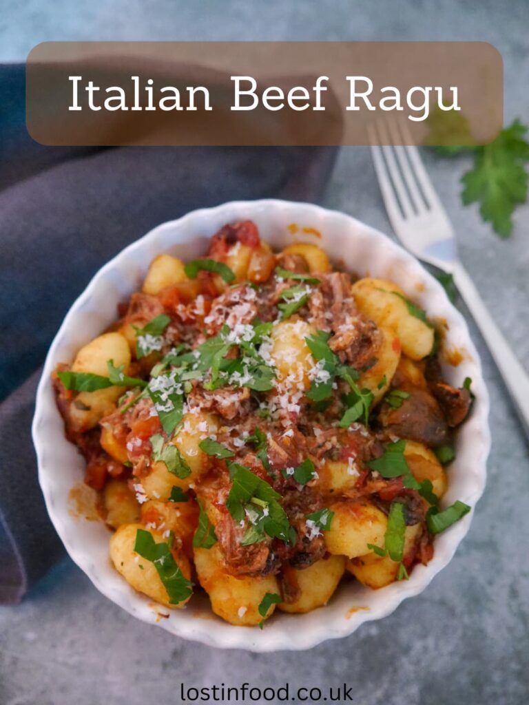 Pinnable image with recipe title and a bowl of Italian beef ragu, served with gnocchi and garnished with fresh parsley and grated parmesan cheese.
