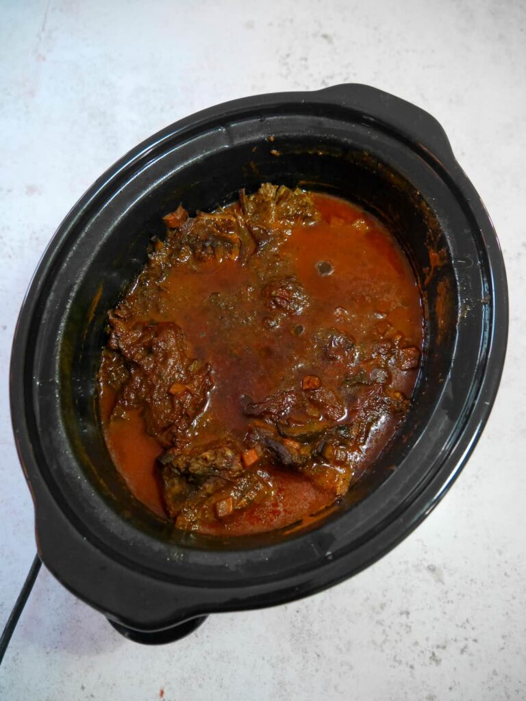 A slow cooker bowl filled with cooked beef ragu.