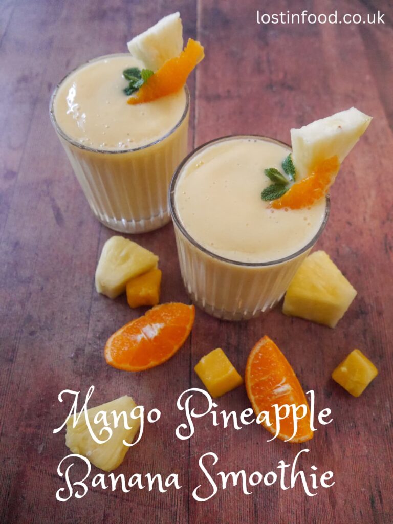 Pinnable image with recipe title and two glasses filled with tropical smoothie, garnished with a wedge of fresh pineapple and slice of clementine.