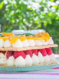 Peach and raspberry mille feuille pastry dessert on a green plate.