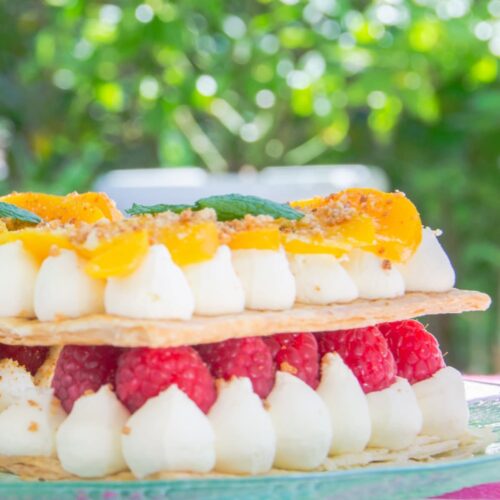 Peach and raspberry mille feuille pastry dessert on a green plate.