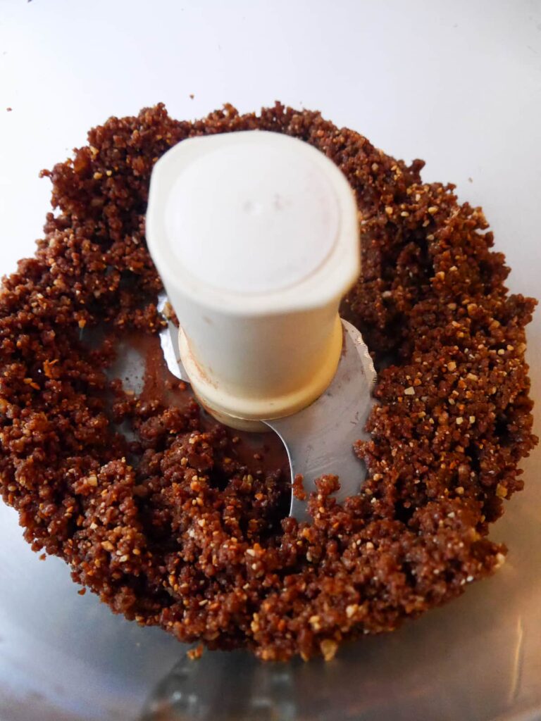 A food processor bowl filled with blitzed peanut butter date energy ball mixture.