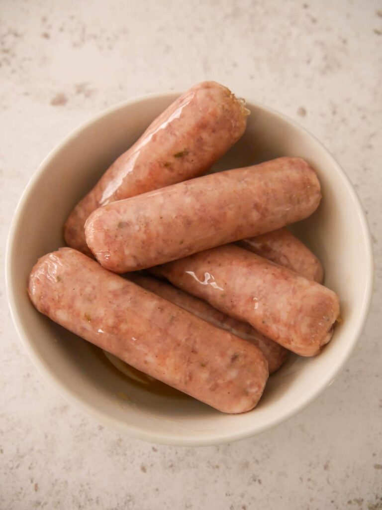 Pork sausages in a dish covered with maple syrup.