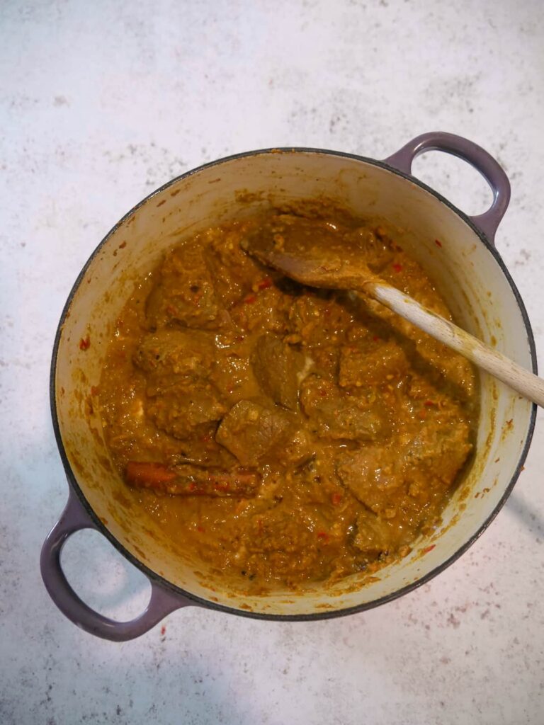A Dutch oven with beef rendang recipe ingredients mixed together.