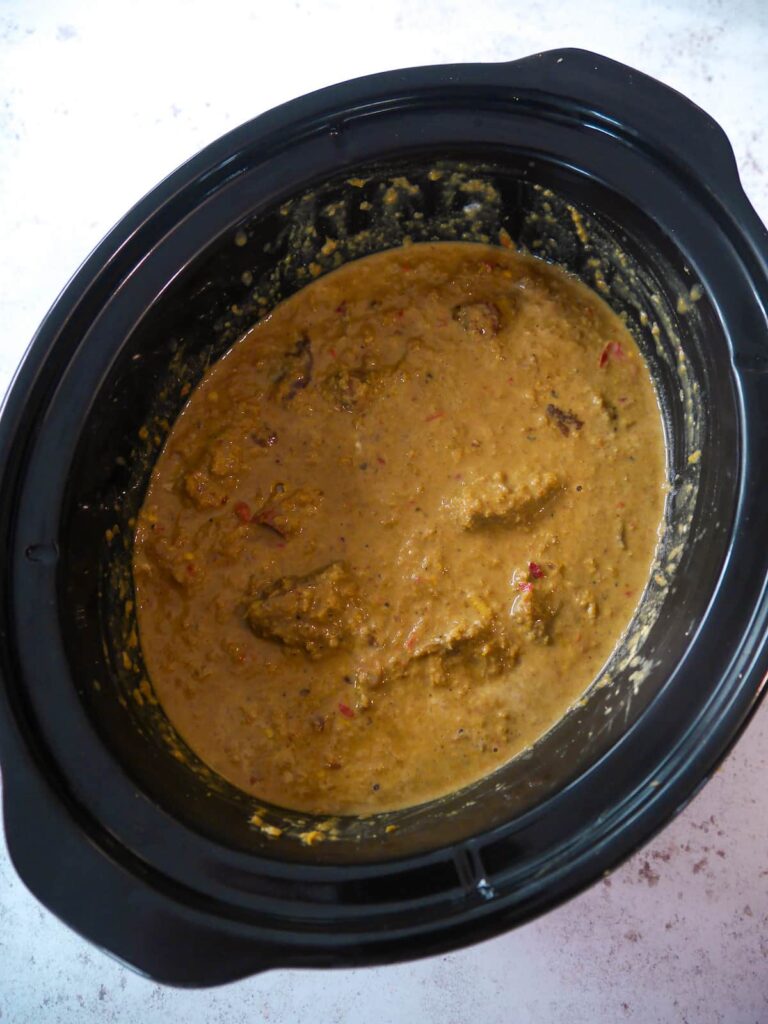 Slow cooker with beef rendang recipe ingredients mixed together.