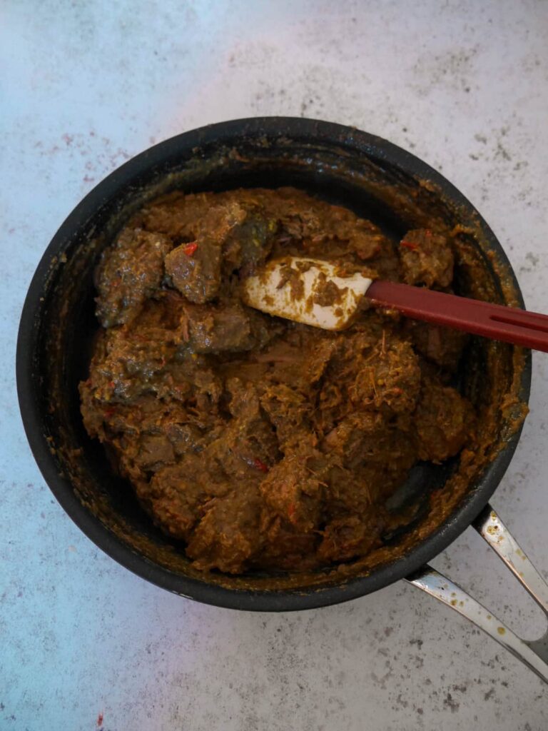 A reduced beef rendang sauce with the cooked chunks of beef added back into the pan.