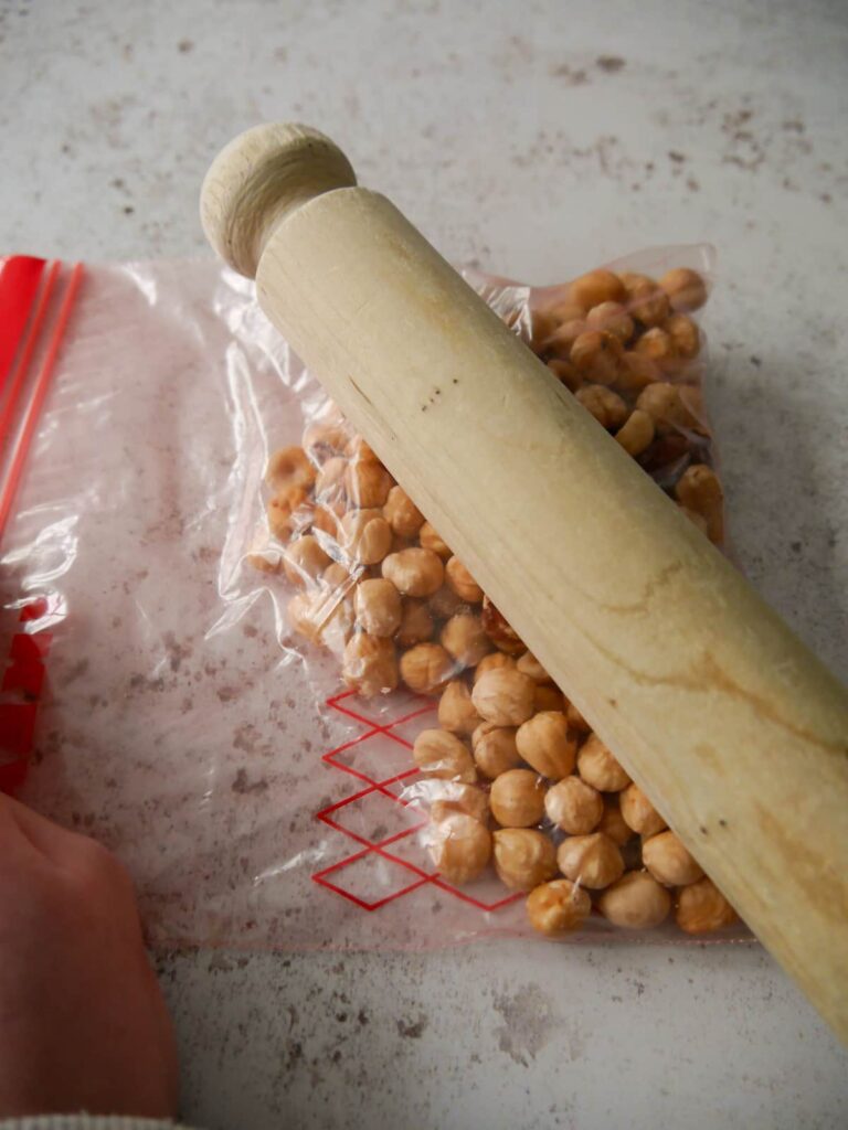 A bag of hazelnuts being broken down with a rolling pin.