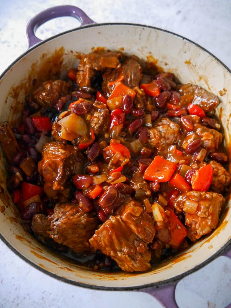 A Dutch oven filled with the ingredients for a chunky beef chilli.