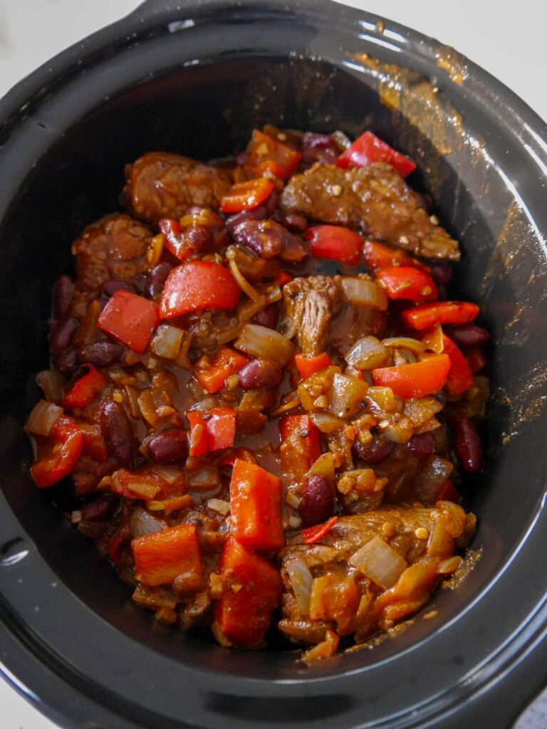 A slow cooker filled with the ingredients for slow cooker chunky beef chilli.