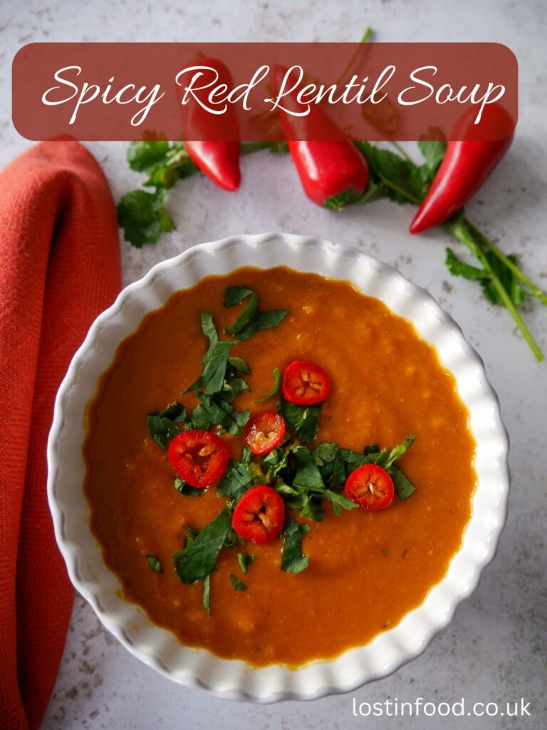 Pinnable image with recipe title and a white bowl of spicy red lentil soup garnished with chopped coriander leaf and thinly spiced red chilli.