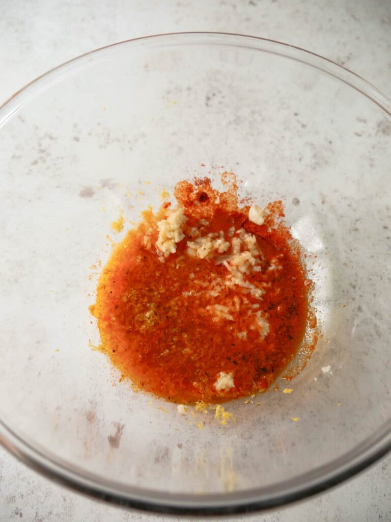 A glass bowl with filled with lemon paprika marinade.