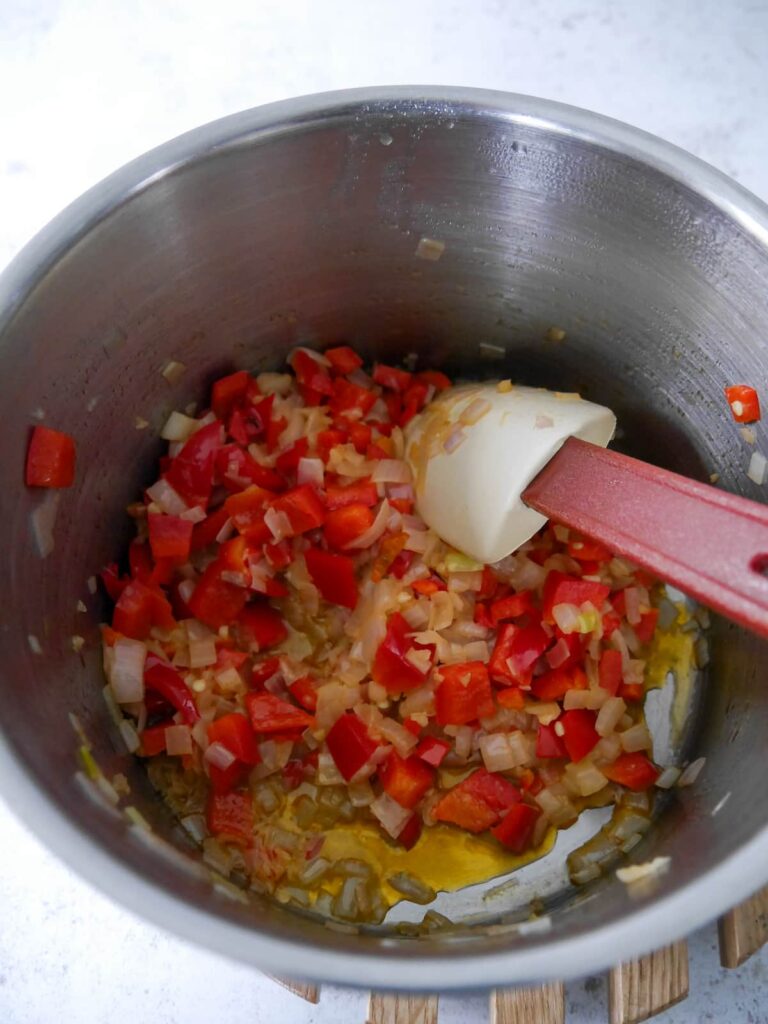 A pan of sauteed shallot, red bell pepper, chilli and garlic.