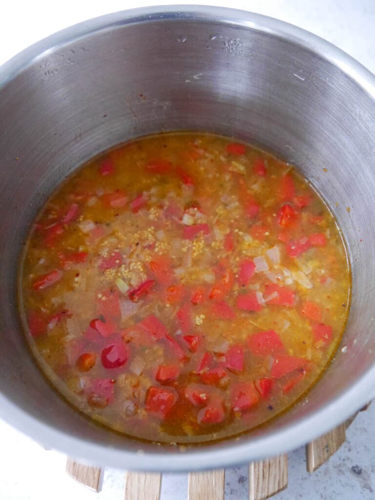 A pan of sauteed vegetables and couscous covered with vegetable stock.
