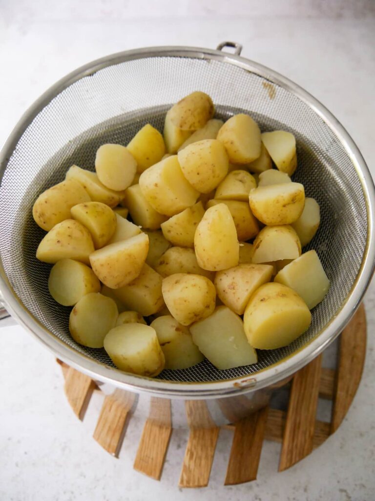 A sieve filled with diced, cooked new potatoes.