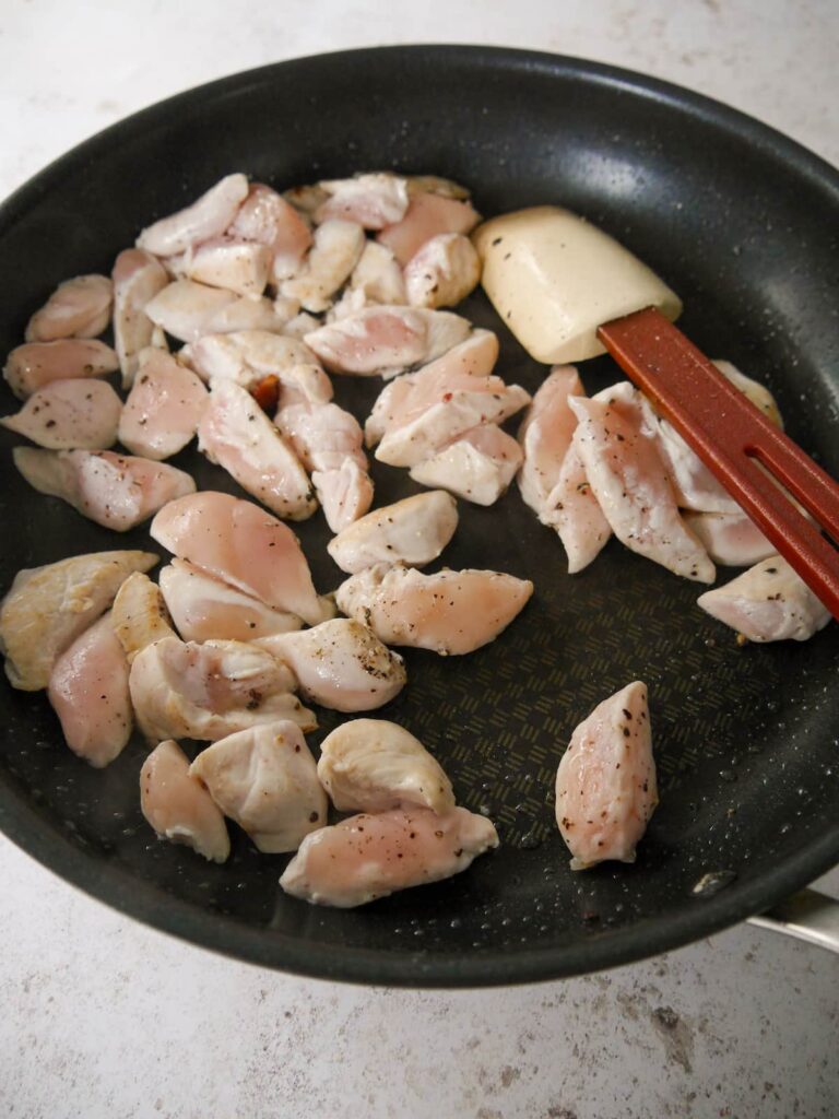 A nonstick frying pan filled with sauteed chicken strips.