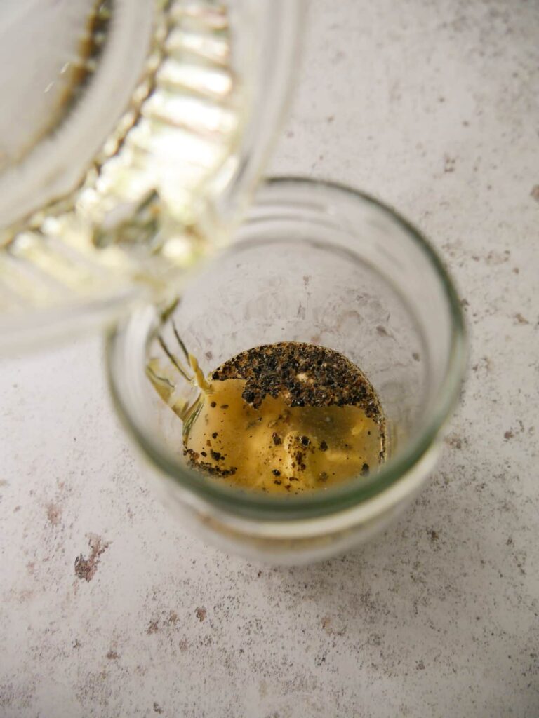 Sunflower oil being poured into a jar with Dijon mustard, white wine vinegar and seasoning.