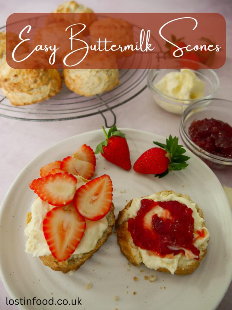 Pinnable image with recipe title and a wire rack topped with buttermilk scones and a plate with a cut scone topped with clotted cream, strawberry jam and slices of fresh strawberries.