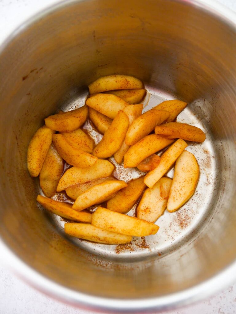 A saucepan filled with cooked cinnamon apple slices.