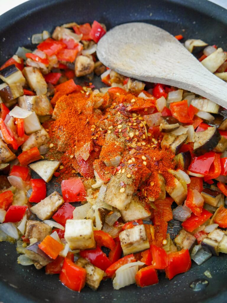 A large frying pan with sauteed vegetables with added dry spices.