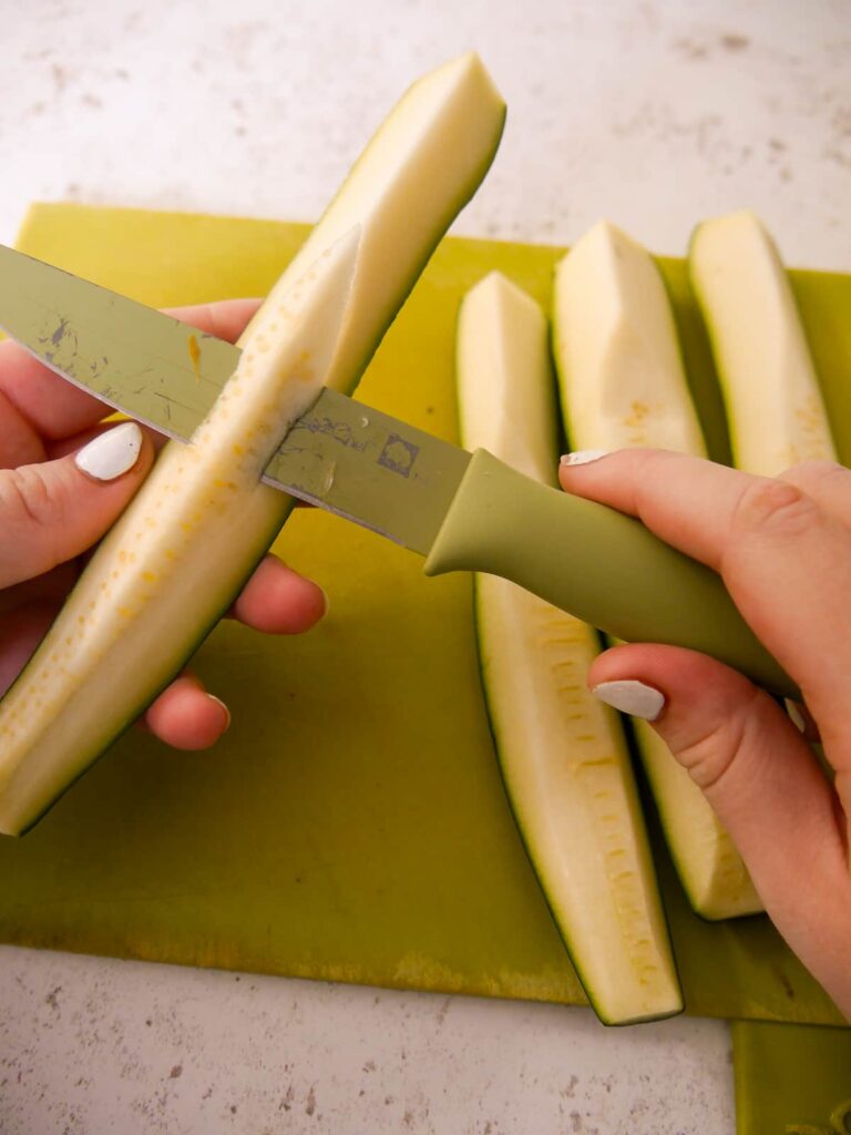 Courgette quartered lengthwise with the soft core being removed with a knife.