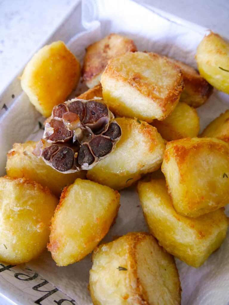 A dish of roast potatoes, lined with kitchen paper to soak up excess oil.