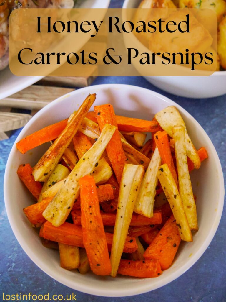 Pinnable image with recipe title and a bowl of honey roasted carrots and parsnips with roast potatoes and turkey set alongside.