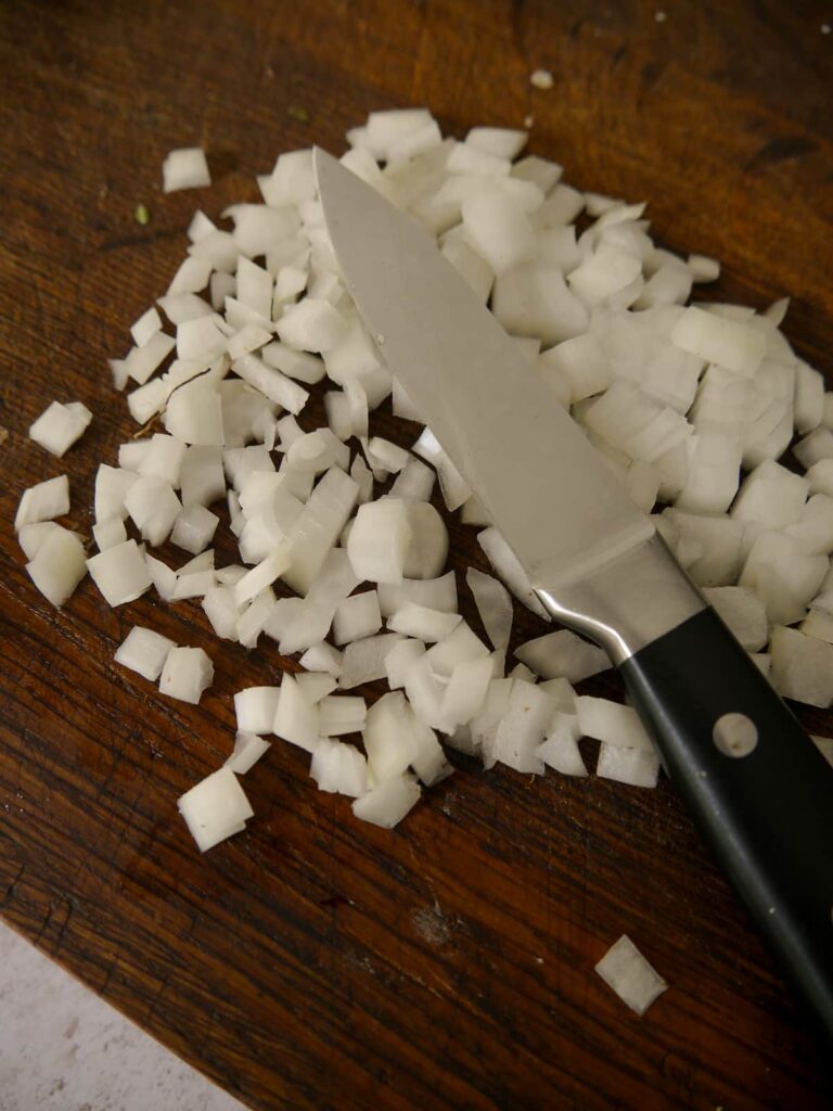 A chopping board topped with small pieces of diced onion.