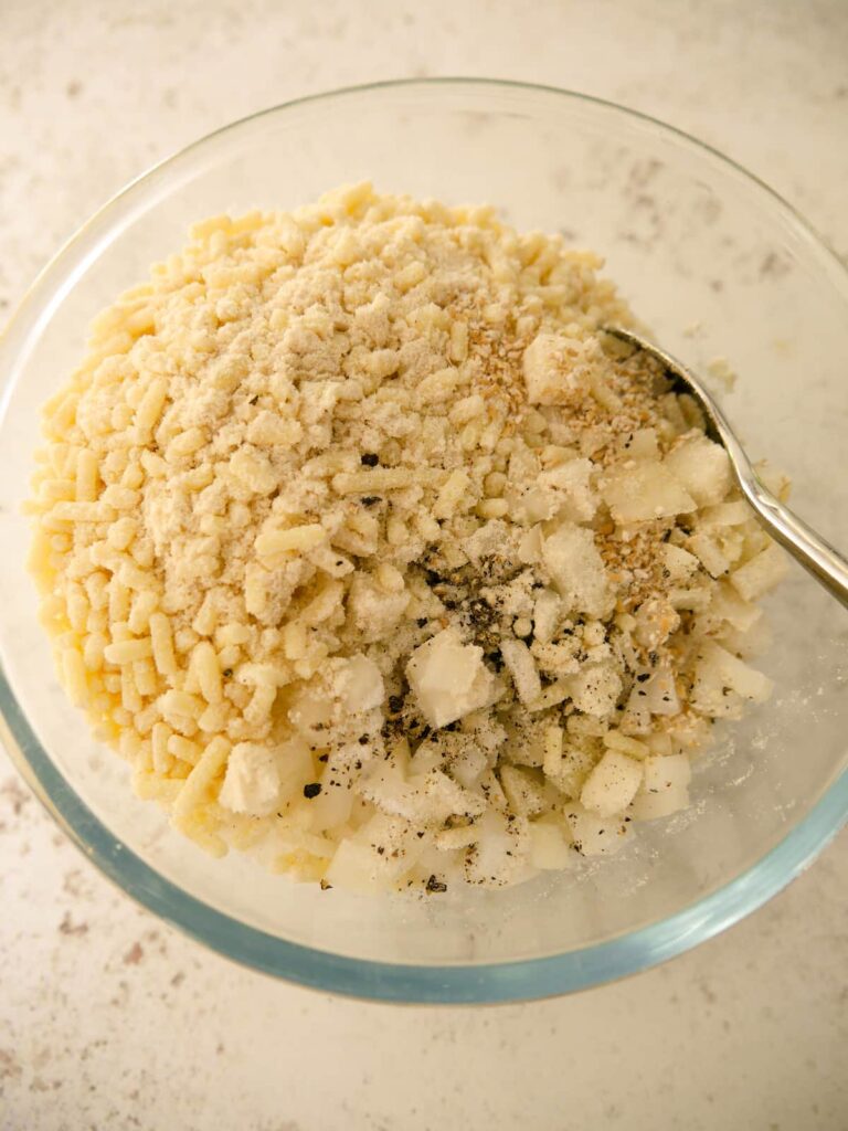 A pyrex glass bowl filled with oatmeal, suet, chopped onion, salt and pepper.