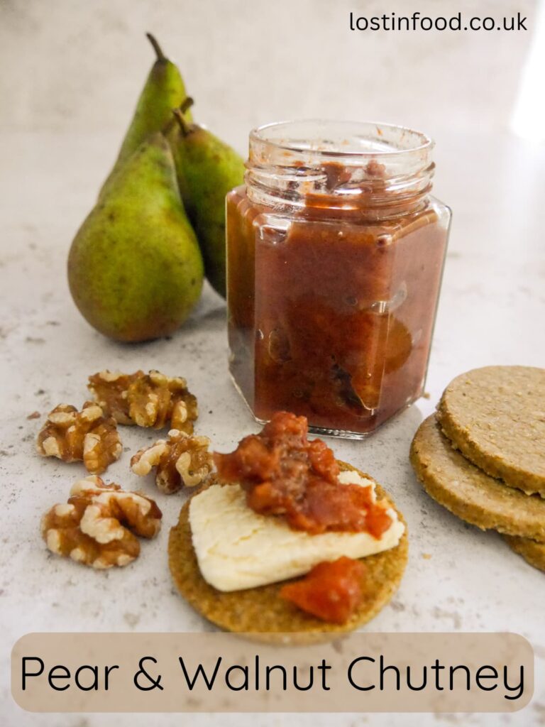 Pinnable image with recipe title and a jar of pear and walnut chutney, with pears, walnuts and cheese and chutney topped oatcakes set alongside.