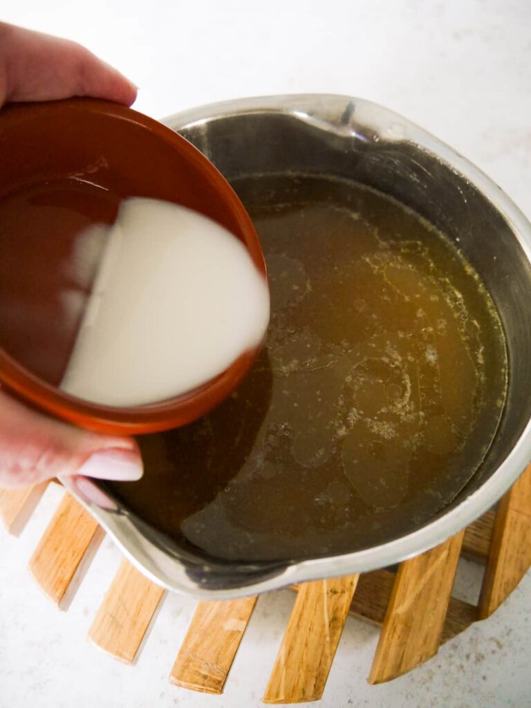 Cornflour being added to a saucepan of turkey gravy.