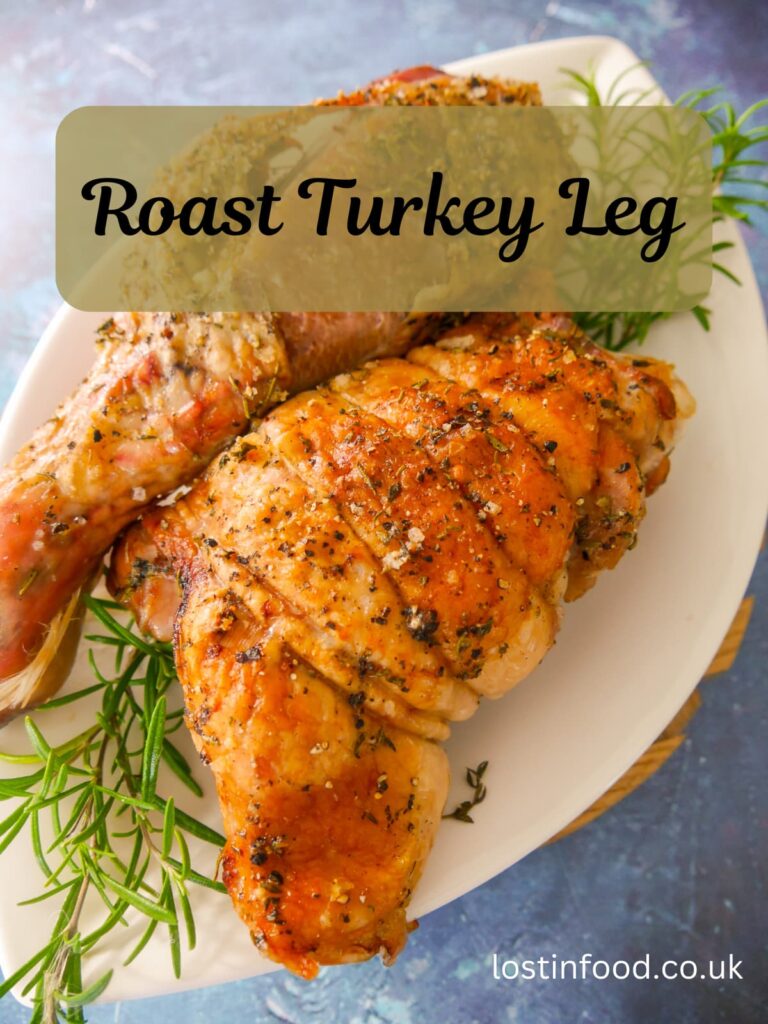 Pinnable image with recipe title and roasted turkey drumstick and thigh set on a white plate garnished with sprigs of fresh rosemary.