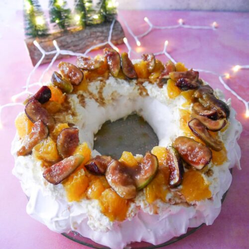 Christmas pavlova wreath topped with fresh orange segments and warm figs and syrup.