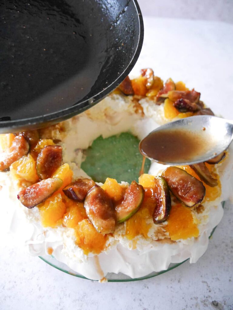 Fig syrup being drizzled over the top of a pavlova.