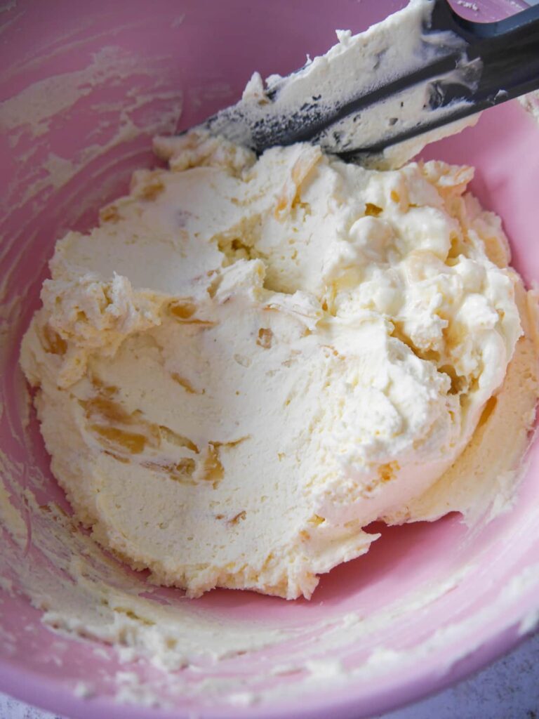 A bowl of whipped cream with added grated stem ginger and ginger syrup.