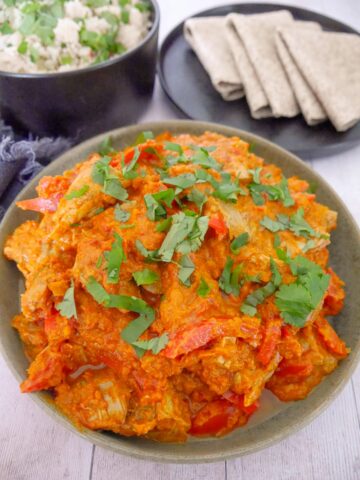 A bowl of leftover turkey curry, serve with sides of chapati flat breads and a bowl of steamed white rice.