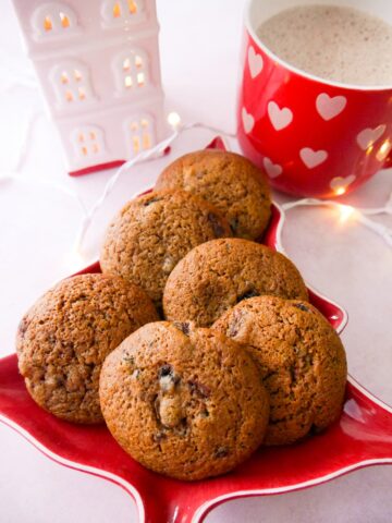 A plate topped with mincemeat cookies with a mug of hot chocolate set alongside.