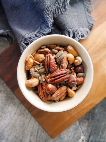 A bowl of salt and vinegar nuts placed on a wooden board.