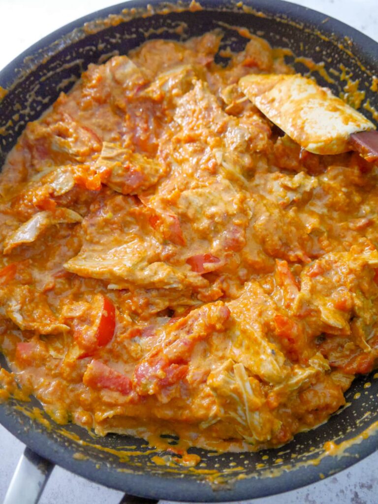 A large non stick frying pan filled with turkey curry with added cream.