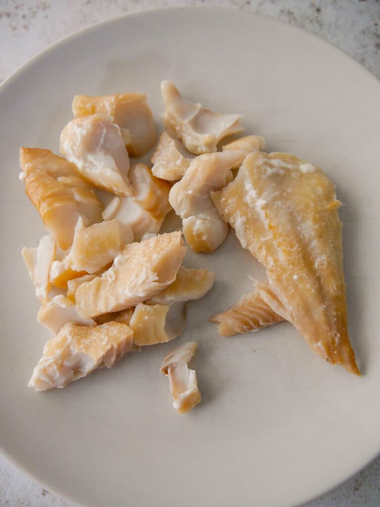 A plate with pieces of poached smoked haddock fillet.