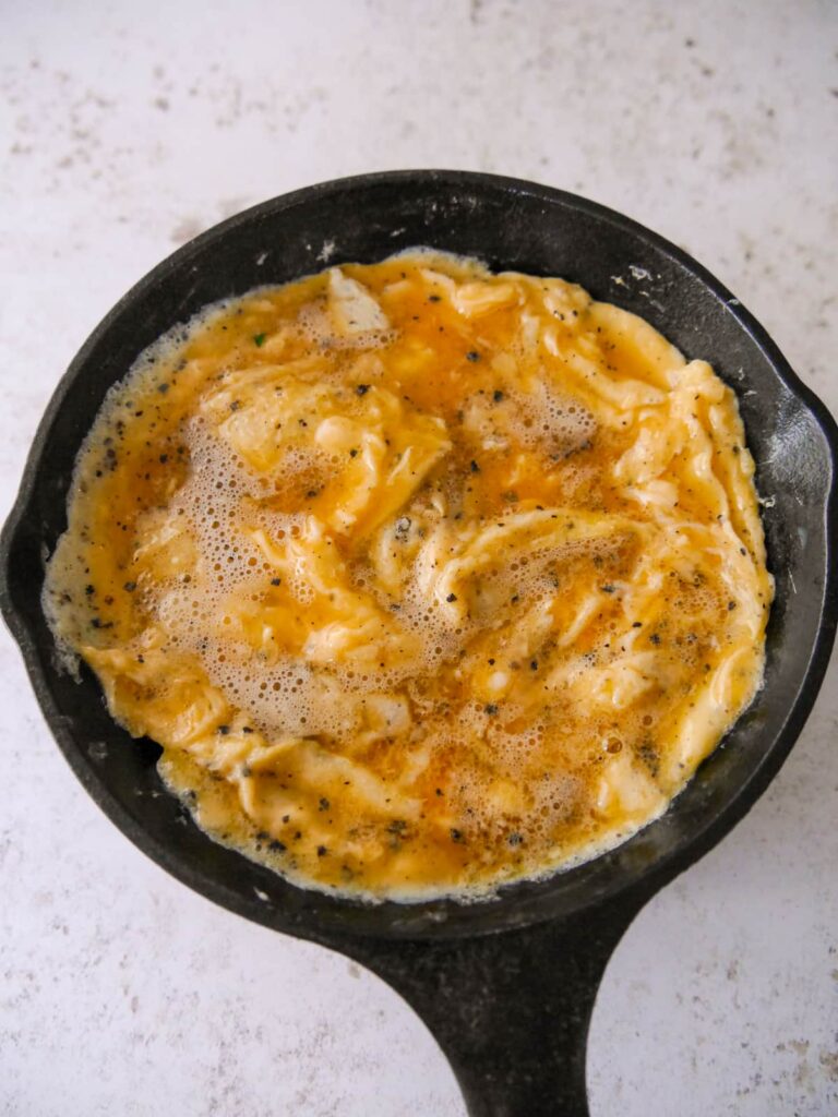 A cast iron skillet with a cooked omelette base.